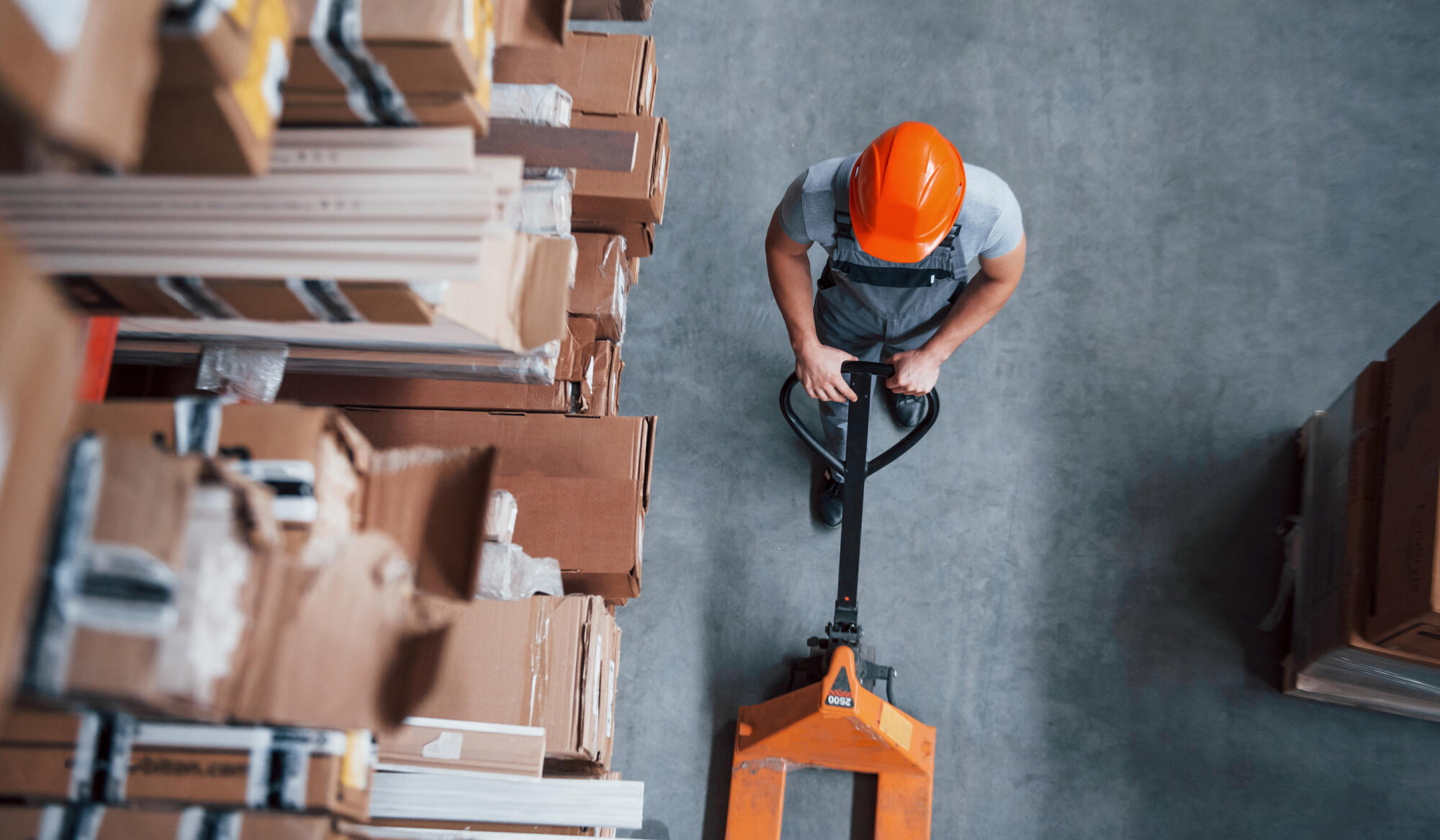 Top view of male worker in warehouse with pallet truck